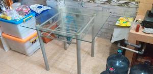 a glass table in a kitchen with a refrigerator at Teras damai Minangkabau in Duku