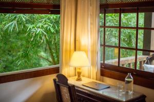 a table with a lamp and a laptop on it next to a window at Pousada Santa Martha in Ubatuba