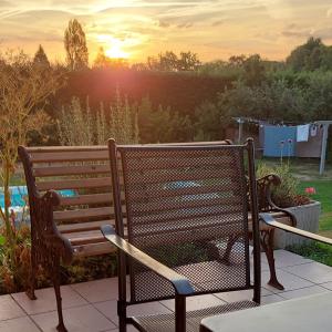 ławka siedząca na patio z zachodem słońca w tle w obiekcie Villa Maëlla - 2 gîtes - jardin, piscine et SPA privés w mieście Saint-Michel-Tubœuf
