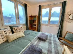 Un dormitorio con una cama y dos grandes ventanales. en Apartment Chamonix Brise du Mont, en Chamonix-Mont-Blanc