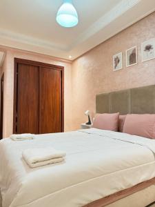 a bedroom with a large white bed with pink pillows at SUITOUISS - Agdal 2 - Appartements à 2 minutes de la gare de train TGV Rabat in Rabat +47 photos