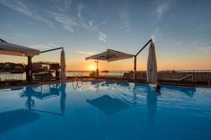 a swimming pool with a sunset in the background at BO Hotel Palazzo in Poreč