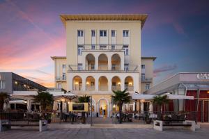 a building with tables and umbrellas in front of it at BO Hotel Palazzo in Poreč