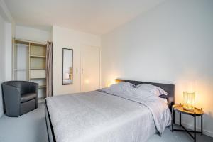 a bedroom with a large bed and a chair at Appart Standing in Trappes