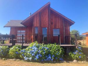 a wooden cabin with flowers in front of it at Kumewe Lodge & Cabañas in Panguipulli