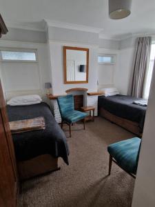 a hotel room with two beds and a chair at Avon Manor Guest House in Lee-on-the-Solent