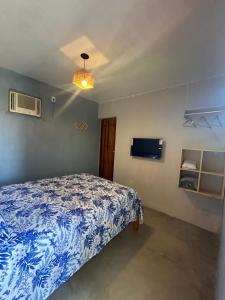 a bedroom with a bed with a blue comforter at Casa da Pri Suítes in Pôrto de Pedras