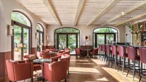 a restaurant with red chairs and tables and windows at Coquillade Provence - Relais & Châteaux in Gargas