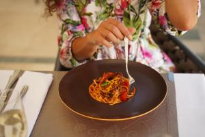 a woman eating spaghetti on a plate with a fork at BO Hotel Palazzo in Poreč