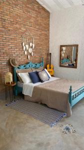 een slaapkamer met een groot bed en een bakstenen muur bij Quintal de Casa in São João Batista do Glória