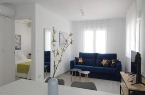 a living room with a blue couch and a bedroom at Olivia Apartments TRG in Benidorm