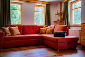 a red couch in a living room with windows at Ferienwohnung Villa Oben im Sandsteinidyll in Rathen