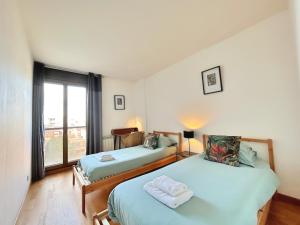 two beds in a room with a window at L'Aérien- Parking- Centre ville - Calme in Toulouse