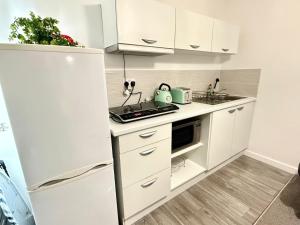 une cuisine avec des armoires blanches et un réfrigérateur blanc dans l'établissement Luxury 1-Bedroom Flat, Wi-Fi, Near Oxford centre, à Oxford 11 autres photos