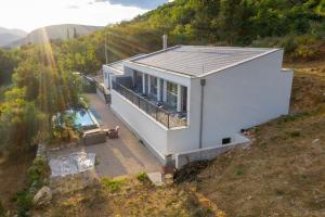 een klein wit huis op een heuvel met een zwembad bij La Finca Olivetree in Šestanovac