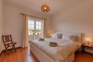 a bedroom with a large bed with a chair and a window at Villa Casa Branca in Ribamar