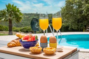 two glasses of orange juice and eggs and bread on a table at Villa Casa Branca in Ribamar