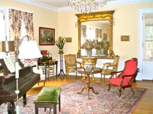 a living room with a piano and a mirror at Whistler's Inn in Lenox