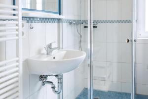 a white bathroom with a sink and a shower at Reethaus Löwe In Beckerwitz in Gramkow