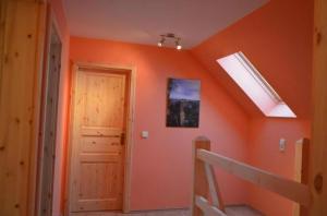 Una habitación naranja con una puerta y un tragaluz. en Ferienhaus Haus Bärenstein In Naundorf Mit Grill, Terrasse, Sauna Und Kaminofen, en Struppen