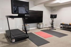 Una habitación con TV de pantalla plana y un gimnasio. en Golf Oasis Sleeps 22! Hot tub Firepit Gym Pool, en Omaha