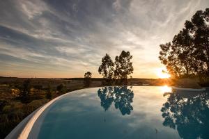 ein Swimmingpool mit der Spiegelung des Sonnenuntergangs in der Unterkunft Herdade do Gamito in Crato