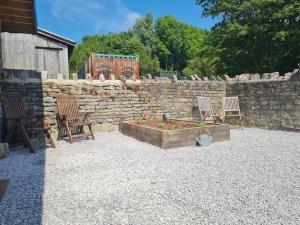 a patio with two chairs and a stone wall at The Potting Shed in Glastonbury +4 photos