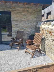 two wooden chairs sitting next to a stone wall at The Potting Shed in Glastonbury