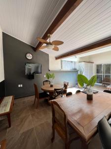 a living room with a ceiling fan and a table at Casa em Maresias in São Sebastião