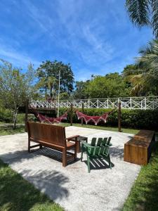 a park with two benches and a table and chairs at Casa em Maresias in São Sebastião