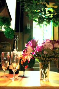 - une bouteille de vin, 2 verres et des fleurs sur une table dans l'établissement Soggiorno Angelus, à Rome