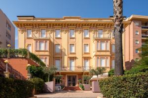 een groot geel gebouw met een boom ervoor bij Hotel Careni Villa Italia in Finale Ligure