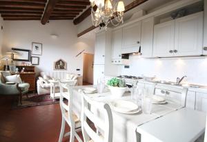 Una cocina con gabinetes blancos y una mesa y sillas blancas. en Zaffiro Bianco, en San Gimignano