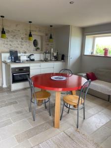 a kitchen with a red table and chairs in a room at Domaine Clos Carron Gîte 2 personnes L'Olivier in Saint-Amour-Bellevue