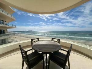 a table and chairs in a balcony with a view of the beach at Paradise Found Luxe 2BR Condo in Iconic Location in Puerto Peñasco