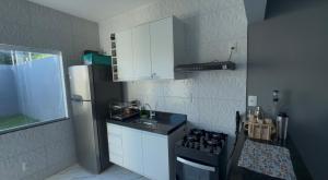 a kitchen with white cabinets and a black stove at CASa LUAR DA BARRA in Barra dos Coqueiros