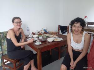 two women sitting at a table in a room at BB villa - Rekawa in Netolpitiya