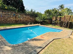 a blue swimming pool with a hose in a yard at Home 11 Strydom in Nelspruit
