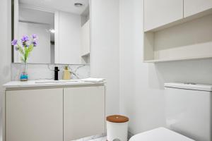 KeysboroughClassy Spaces Keysborough - New 2 Storey Townhouse的白色的浴室,配有水槽和紫色花瓶