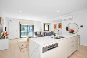 a white kitchen with a sink and a living room at Classy Spaces Keysborough - New 2 Storey Townhouse in Keysborough