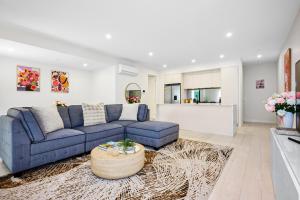 KeysboroughClassy Spaces Keysborough - New 2 Storey Townhouse的客厅里有一张蓝色的沙发和一张桌子