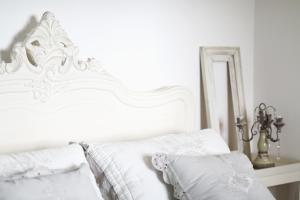 uma cama branca com lençóis e almofadas brancos em Zaffiro Bianco em San Gimignano