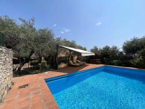 a blue swimming pool in a yard with trees at Villa Tellaro 8 Pax by VILLASRETREATS in Tellaro