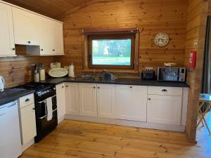 a kitchen with white cabinets and a window in a cabin at Woodpecker Lodge in Market Rasen +17 photos