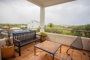 porche con banco y sillas en el balcón en Apartamento en Residencia Jardines de Asilah, en Asilah