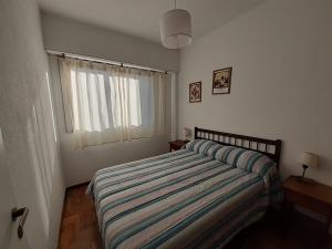 a bedroom with a bed with a striped comforter and a window at Depto 2 amb zona centro con cochera Solo familias in Mar del Plata