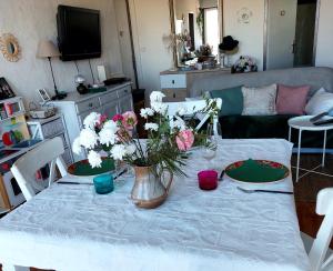 a living room with a table with flowers on it at Chambre chez l'habitante avec salle de bain et cuisine communes - Présence d'un chat in Bordeaux