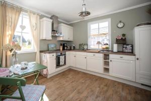 a kitchen with white cabinets and a table in it at Ferienhaus In Ummanz Mit Sauna, Garten Und Grill in Ummanz +26 photos