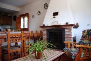 a living room with a fireplace and a table and chairs at Casa Número 3 in Válor +32 photos
