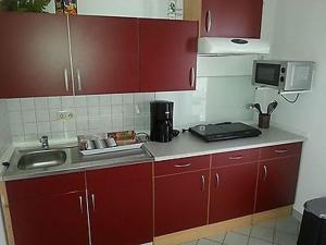 una cucina con mobili rossi e un lavandino di Fewo Fam Große a Friedland